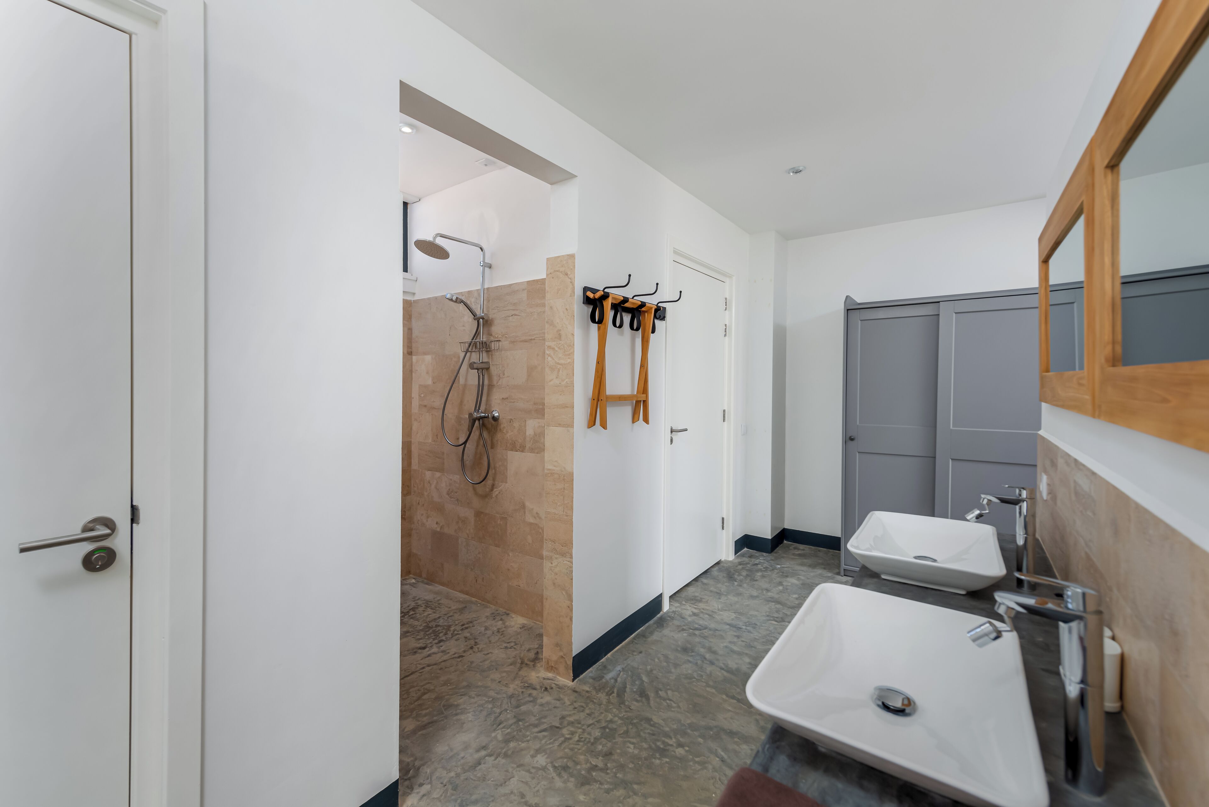 A modern bathroom with two sinks, a shower, and a mirror.