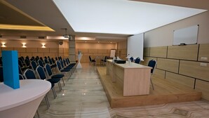 A conference room with a long table, chairs, a podium, and a whiteboard. - Royal Grand Hotel & Spa (Kavarna)