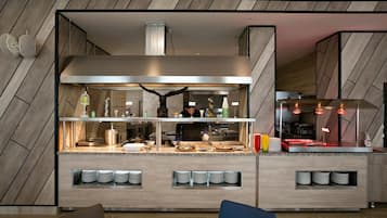 A modern kitchen with a chef preparing food, a built-in stove, and a counter with plates and utensils.