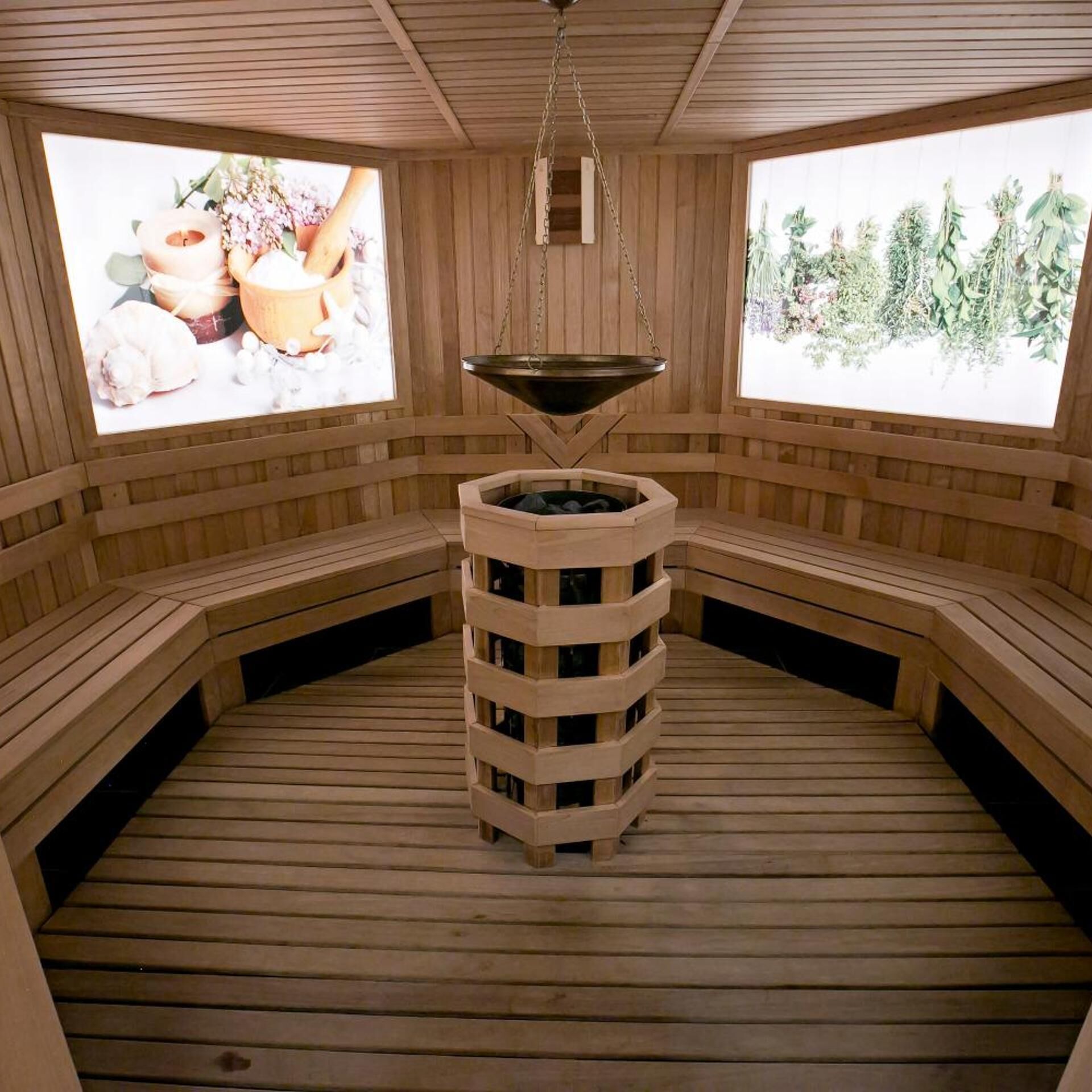 A sauna with wooden benches, a central pillar, and two windows with natural views.