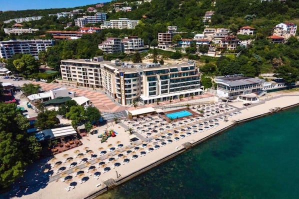 A coastal hotel with multiple floors, a swimming pool, and a beach area with sun loungers. - Royal Grand Hotel & Spa (Kavarna)