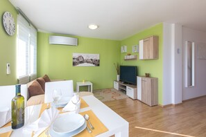 Un salon moderne comprenant un coin repas, des murs verts, un téléviseur à écran plat et un meuble en bois.