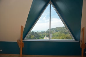 A room with a skylight window offering a view of a green landscape and buildings.