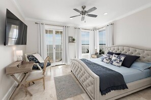 A bedroom with a large bed, a desk, a chair, and a ceiling fan.
