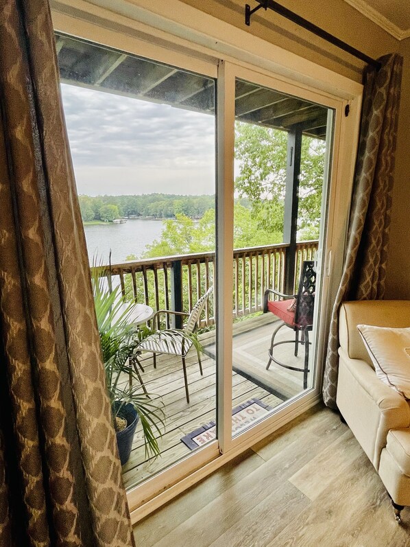 A room with a sliding glass door leading to a balcony. The balcony has a wooden deck, a chair, and a table. - Relax & Enjoy beautiful Sunsets! * Boating Packages Available! (Hot Springs)
