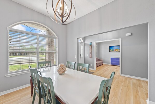 A dining area with a large table, chairs, and a chandelier.