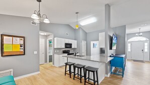 Una cocina moderna con una isla central, taburetes de bar, un microondas y un armario azul.