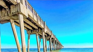 Un muelle de madera que se adentra en el océano, con aguas cristalinas y un cielo despejado.