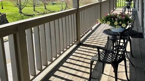 Eine überdachte Veranda mit hängenden Blumenkörben, einer Holzterrasse und Sitzgelegenheiten im Freien.