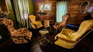 Ein Zimmer mit Holzwänden, einem Spiegel und stuhlförmigen Sitzgelegenheiten mit Blumenmuster.