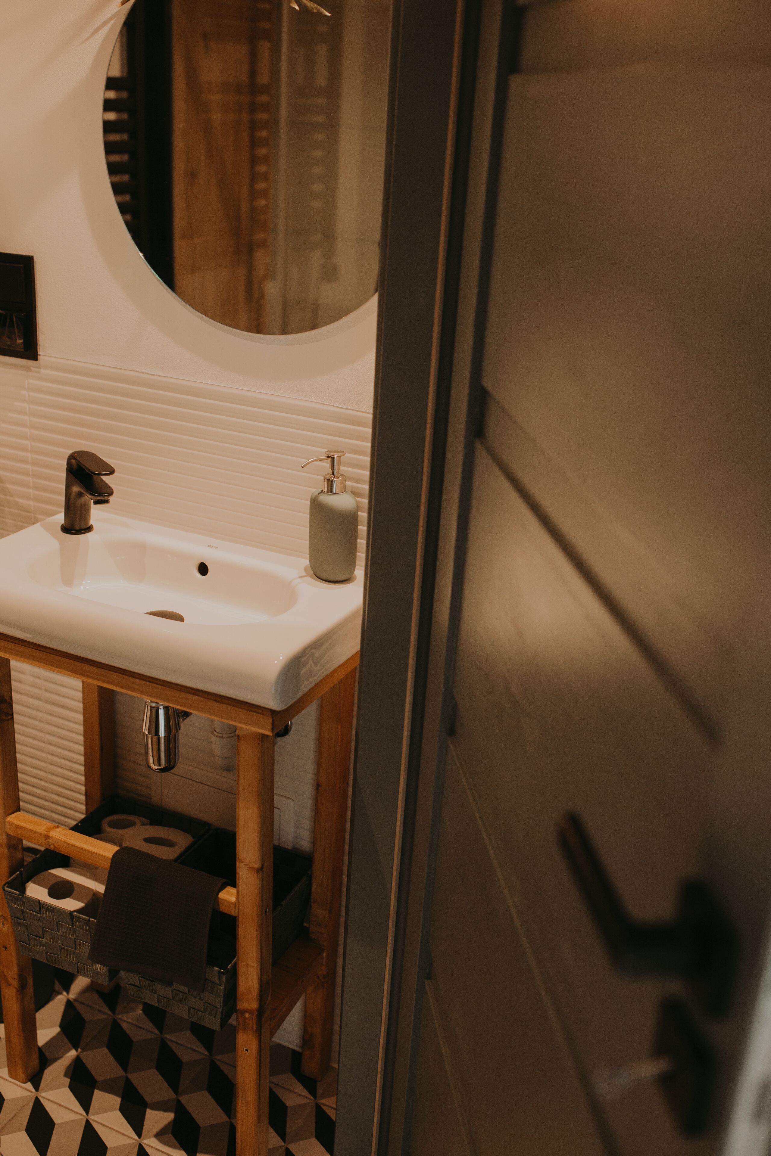 A bathroom with a white sink, wooden cabinet, and a black and white checkered floor.