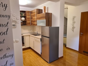 A modern kitchen with wooden cabinets, a stainless steel refrigerator, and a microwave.