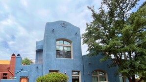 Un edificio blu dallo stile architettonico distintivo, con una grande finestra e un ingresso.