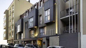 A multi-story hotel with balconies, a ground floor restaurant, and several parked cars. - L Adresse (Saint-Malo)