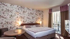 A hotel room with a large bed, two bedside lamps, a round table, and a chair. - L Adresse (Saint-Malo)