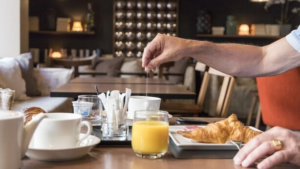 A breakfast setting with a tray containing croissants, orange juice, and a cup of coffee. - L Adresse (Saint-Malo)