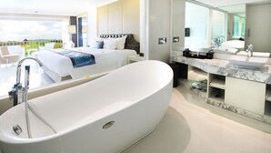 A modern hotel room with a large bathtub, a separate bedroom with a king-sized bed, and a bathroom with a large mirror and marble countertop. - The Rich Prada Bali (Pecatu)
