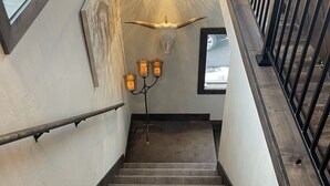 Eine Treppe mit einer Holzhandläufe, einer Wandleuchte und einer Stierkopf-Dekoration.