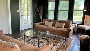 Ein Wohnzimmer mit einem beigefarbenen Sofa, einem Glastisch und einem gemusterten Teppich.