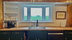 Eine Küche mit integriertem Fenster, Holzschränken, einer Kaffeemaschine und einem Schild mit Bitte um Entsorgung des Mülls.
