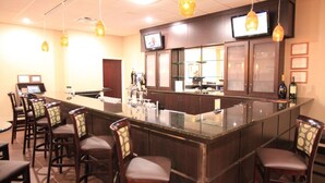 A bar area with a long counter, multiple bar stools, and a television mounted above the counter. - Quality Inn & Suites Downtown Mansfield (Mansfield)