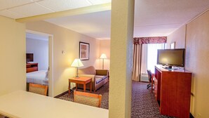 A hotel room with a bed, a desk, a chair, a TV, and a lamp. - Quality Inn & Suites Downtown Mansfield (Mansfield)