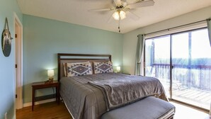 A bedroom with a bed, bedside tables, a ceiling fan, and a view of the outdoors. - Mountain Getaway- Outdoor Pool! Hiking Trails! (Reeds Spring)