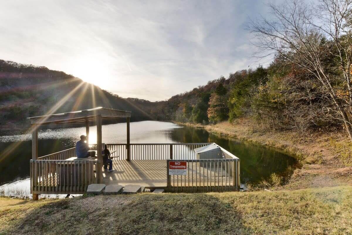 A wooden dock with a gazebo, a no trespassing sign, and a lake.