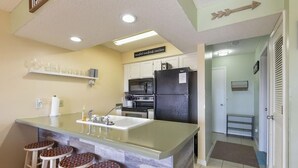 A compact kitchen with a central island, bar stools, a refrigerator, and a microwave. - Mountain Getaway- Outdoor Pool! Hiking Trails! (Reeds Spring)