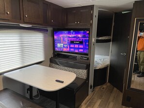 A compact RV interior with a TV, a small table, and a bunk bed. - Delightful RV with campground amenities (Argillite)