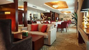 A modern hotel lobby with a sofa, dining area, and a reception desk. - Ramada Plaza by Wyndham Shenyang City Center (Shenyang)