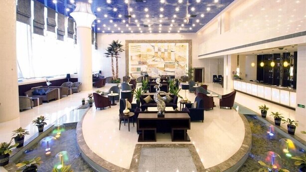 A spacious lobby with a central seating area, a large abstract mural, and a ceiling with numerous lights. - Ramada Plaza by Wyndham Shenyang City Center (Shenyang)