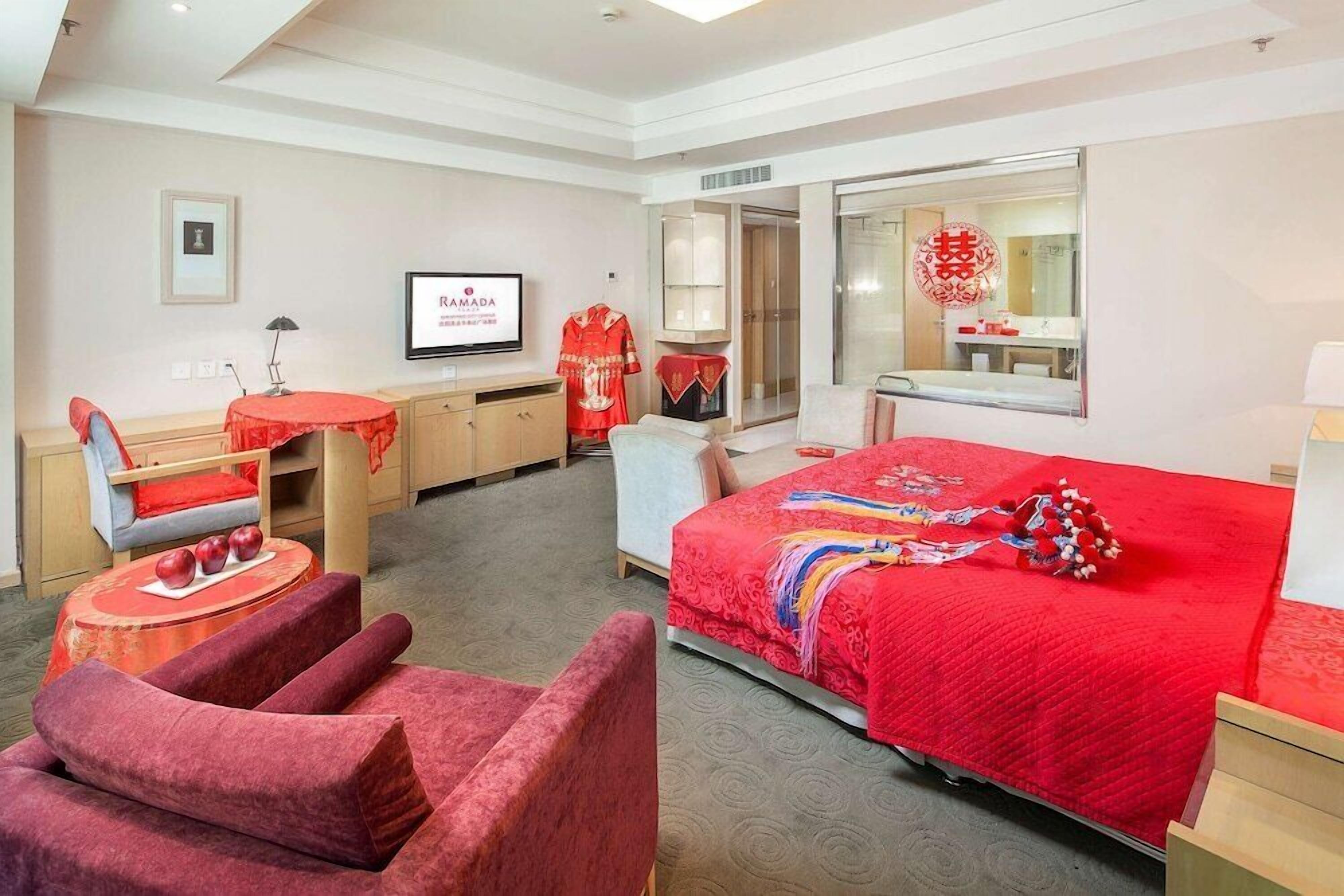 Una habitación de hotel con cama, escritorio, silla, televisor y armario.