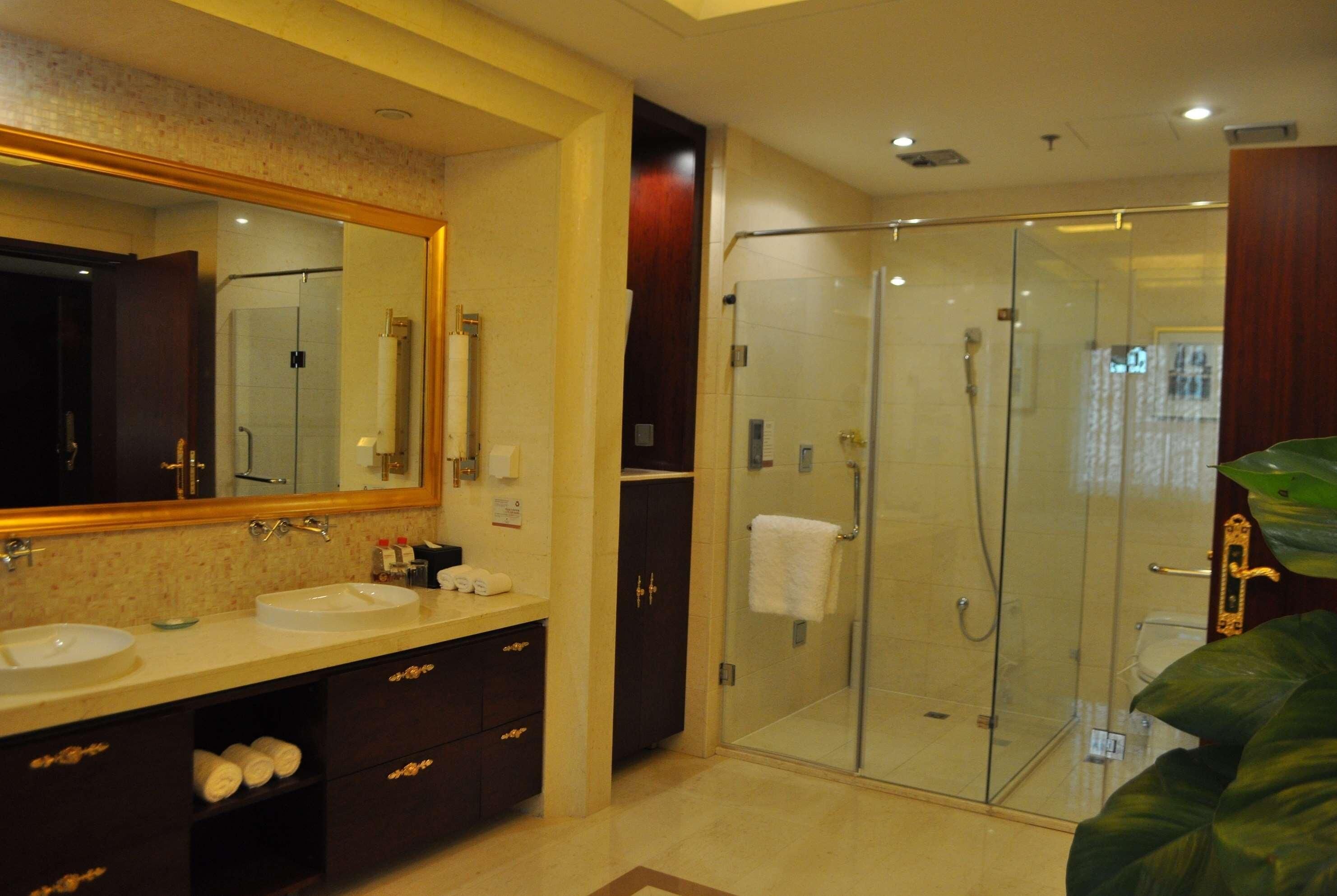 A modern bathroom with two sinks, a large mirror, and a glass-enclosed shower.