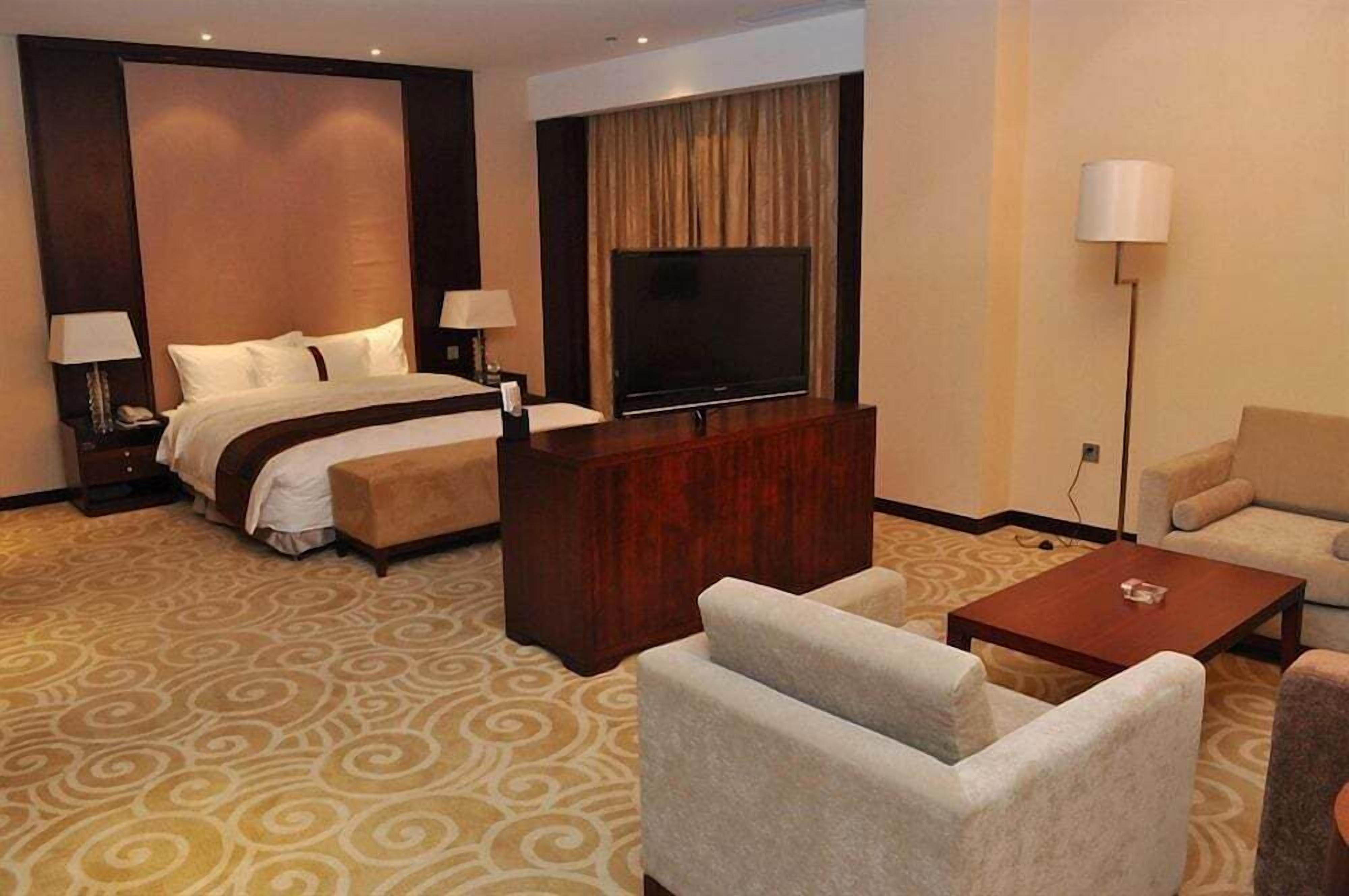 Een hotelkamer met een groot bed, een televisie, een bureau en een bank.