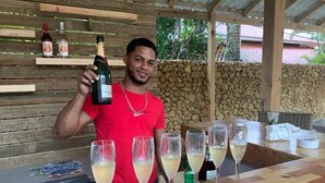 Iemand houdt een champagnefles vast, staand voor een bar met verschillende champagneglazen.