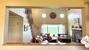 A living room with a fireplace, two couches, a coffee table, and a view through large windows. - Serenity Heights - Peaceful Country Acres with beautiful view in every direction (Osceola)