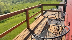 A wooden deck with metal chairs and a railing overlooking a green landscape. - Serenity Heights - Peaceful Country Acres with beautiful view in every direction (Osceola)