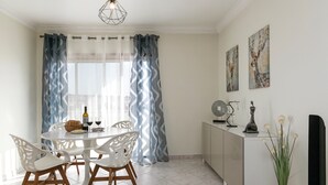 A dining area with a round table, white chairs, a white cabinet, and a vase with plants. - O Sítio do Areal - Bright House in Nazaré (Nazaré)