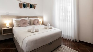 Ein ordentlich bezogenes Bett mit weißen Leinen, einem Holzkopfende und einer Nachttischlampe.