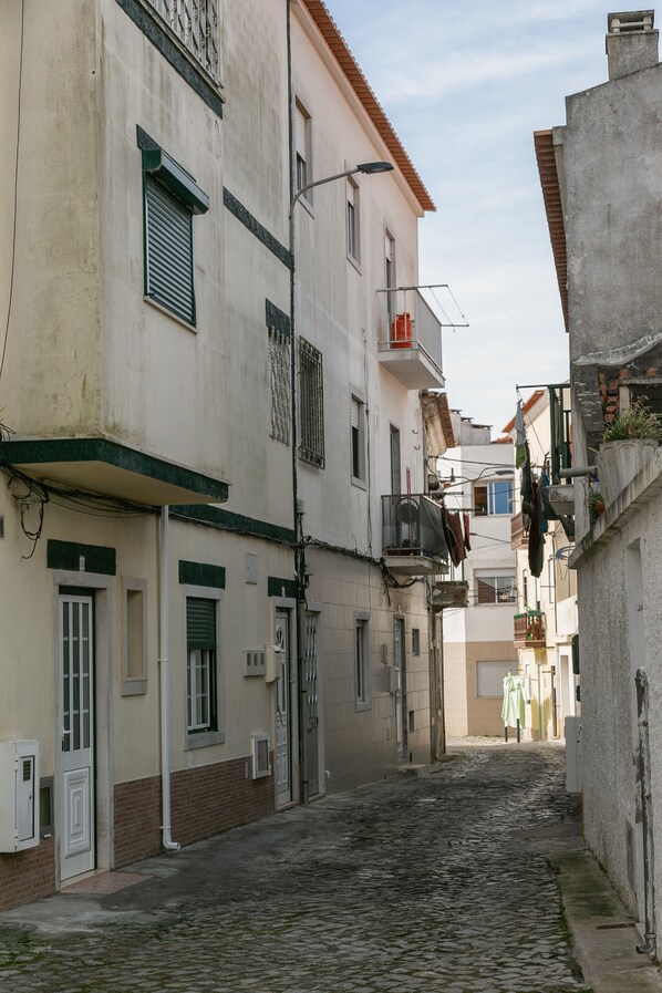 A narrow cobblestone street flanked by buildings with balconies and windows.