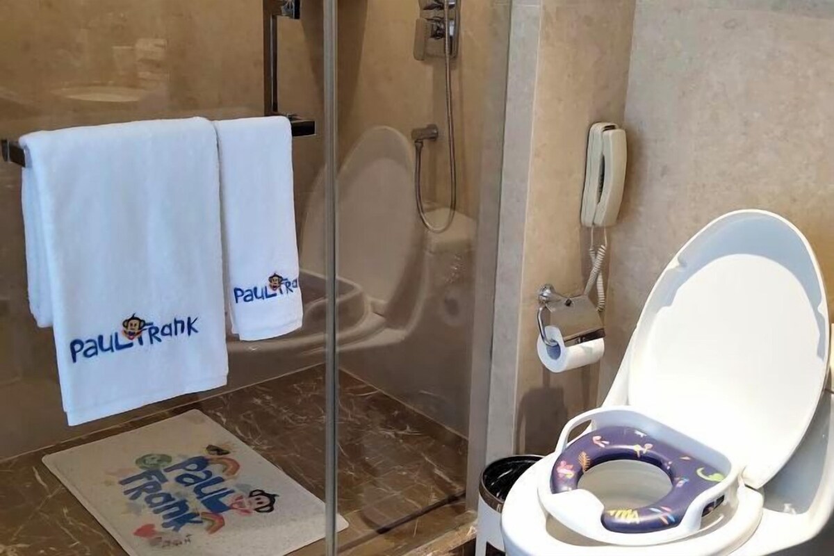 A bathroom with a glass-enclosed shower, a toilet with a child seat, and towels with "Paul Frank" branding.