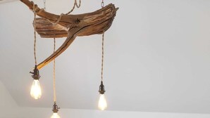 A living room with a dark brown leather sofa, a wooden coffee table with magazines, and a hanging light fixture made of wood. - In the forest in a minute. Cozy vacation apartment on the outskirts of the village. (Velen)