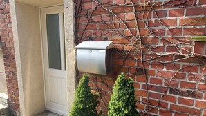 A brick wall with a mailbox, a door, and two potted plants. - In the forest in a minute. Cozy vacation apartment on the outskirts of the village. (Velen)