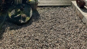 A narrow pathway leading to a wooden deck surrounded by a garden with potted plants and a brick wall. - In the forest in a minute. Cozy vacation apartment on the outskirts of the village. (Velen)