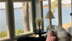Una habitación con vistas a un lago, un ventilador de techo y una mesa con una lámpara y un florero con plantas.