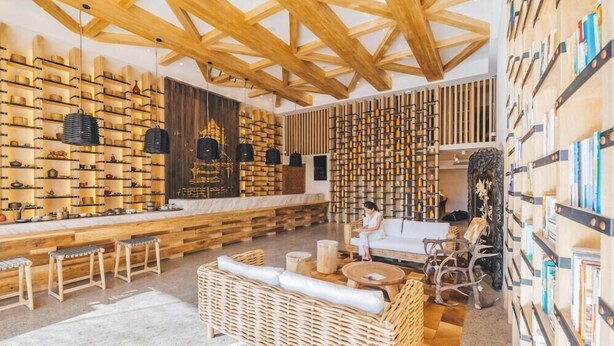 Ett rymligt loungeområde med synliga träbjälkar, en bar med hyllor fulla av flaskor och bekväma sittplatser.
