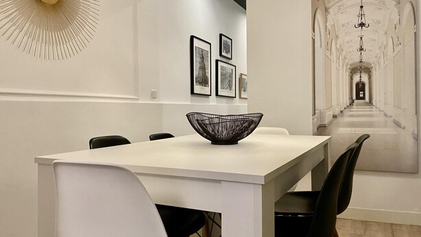 A modern dining area with a white table, black chairs, and a unique black bowl centerpiece. - Malasaña Gallery – 3-Bedroom Apartment in the City Center (Madrid)