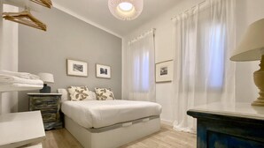 A bedroom with a bed, a dresser, a nightstand, and a lamp. - Malasaña Gallery – 3-Bedroom Apartment in the City Center (Madrid)