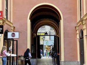 An arched entrance to a building with a sign for 'Brico Gourmet' visible.